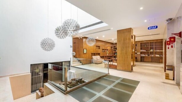 Un intérieur moderne avec un escalier en verre, des étagères en bois et une mezzanine.
