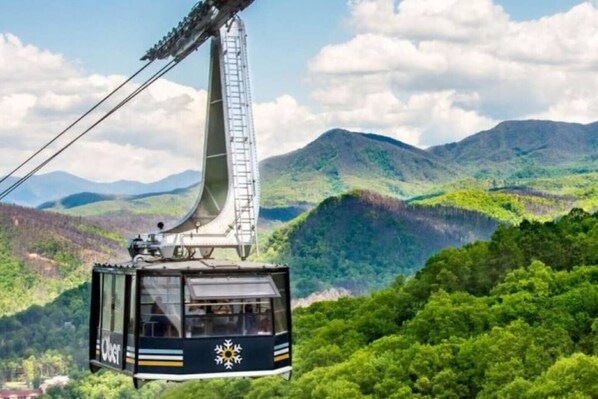 A cable car with a transparent cabin, offering a view of lush green mountains.