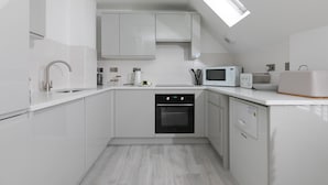 Eine moderne Küche mit weißen Schränken, einem eingebauten Ofen, einer Mikrowelle und einem Oberlicht.