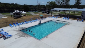 Une piscine avec des chaises longues bleues et un pavillon abrité.
