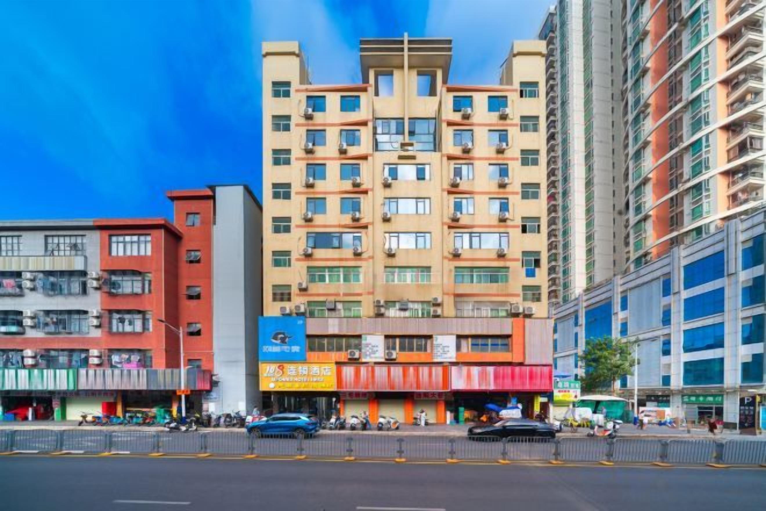 Un immeuble à plusieurs étages, doté d’une façade plane, de plusieurs balcons et d’un espace commercial au niveau du sol, agrémenté d’une enseigne.