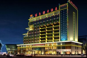 Un hotel de varios pisos con fachada moderna, varios balcones y una señalización llamativa.