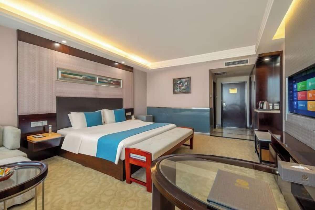 Ein Hotelzimmer mit einem Bett, einem Schreibtisch, einem Stuhl, einem Fernseher und einer Tür.