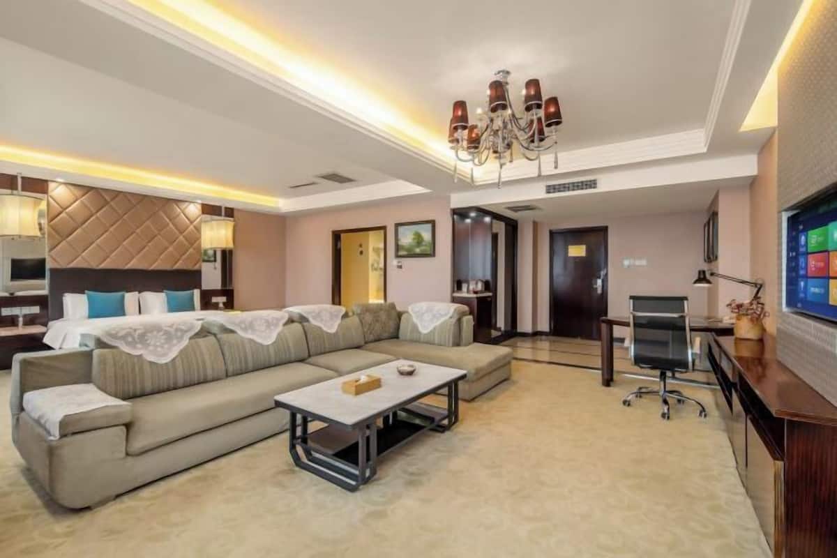 Ein modernes Wohnzimmer mit einem Ecksofa, einem Couchtisch, einem Fernseher und einer Chandelüster.