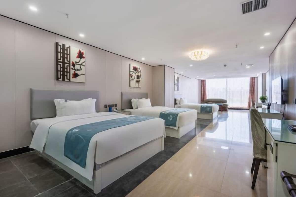 Ein Hotelzimmer mit zwei Betten, einem Schreibtisch und Blick auf die Stadt.