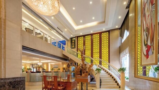 Eine geräumige Lobby mit einer imposanten Treppe, einem Empfangsbereich und einer Sitzecke.