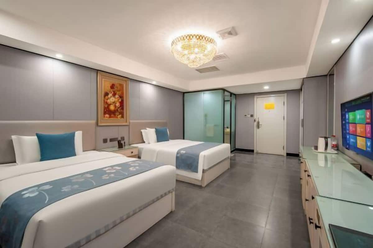 Ein Hotelzimmer mit zwei Betten, einem Glastisch, einer Kristalllüster und einem Bild an der Wand.