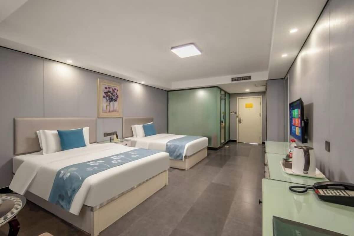 Ein Hotelzimmer mit zwei Betten, einem Schreibtisch mit Telefon und einem Fernseher.