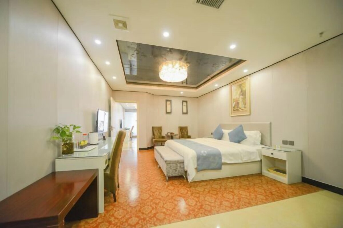 A hotel room with a large bed, bedside tables, a desk, and a chair.