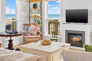 Ein gemütliches Wohnzimmer mit Kamin, Fernseher und Meerblick.