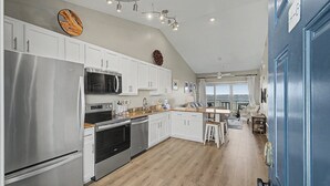 Una cocina moderna con electrodomésticos de acero inoxidable, armarios blancos y piso de madera.