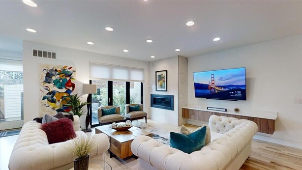 A modern living room with a large flat-screen TV, comfortable seating, and a decorative wall piece.