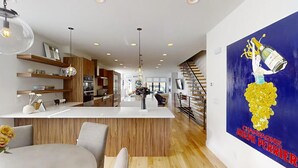 A modern kitchen with a central island, wooden cabinetry, and pendant lighting.