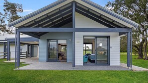 Une maison moderne dotée d’un porche abrité, de grandes portes-fenêtres coulissantes et d’une pelouse bien entretenue.