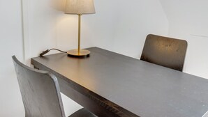A table with a lamp, two chairs, and a power cord.