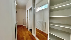 Un couloir étroit avec un plancher en bois, des murs blancs et un radiateur.