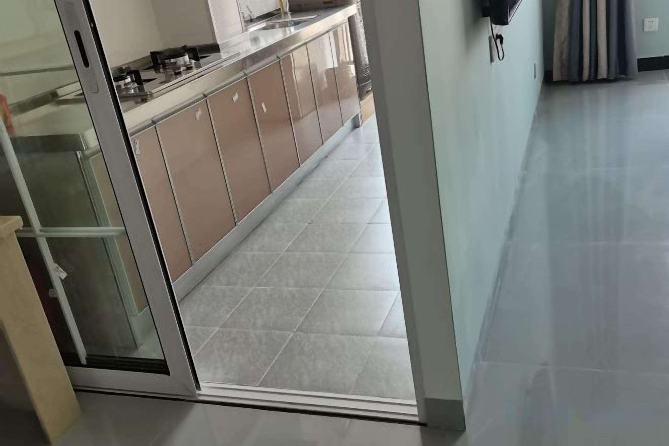 A modern kitchen with a sliding glass door leading to a tiled hallway.