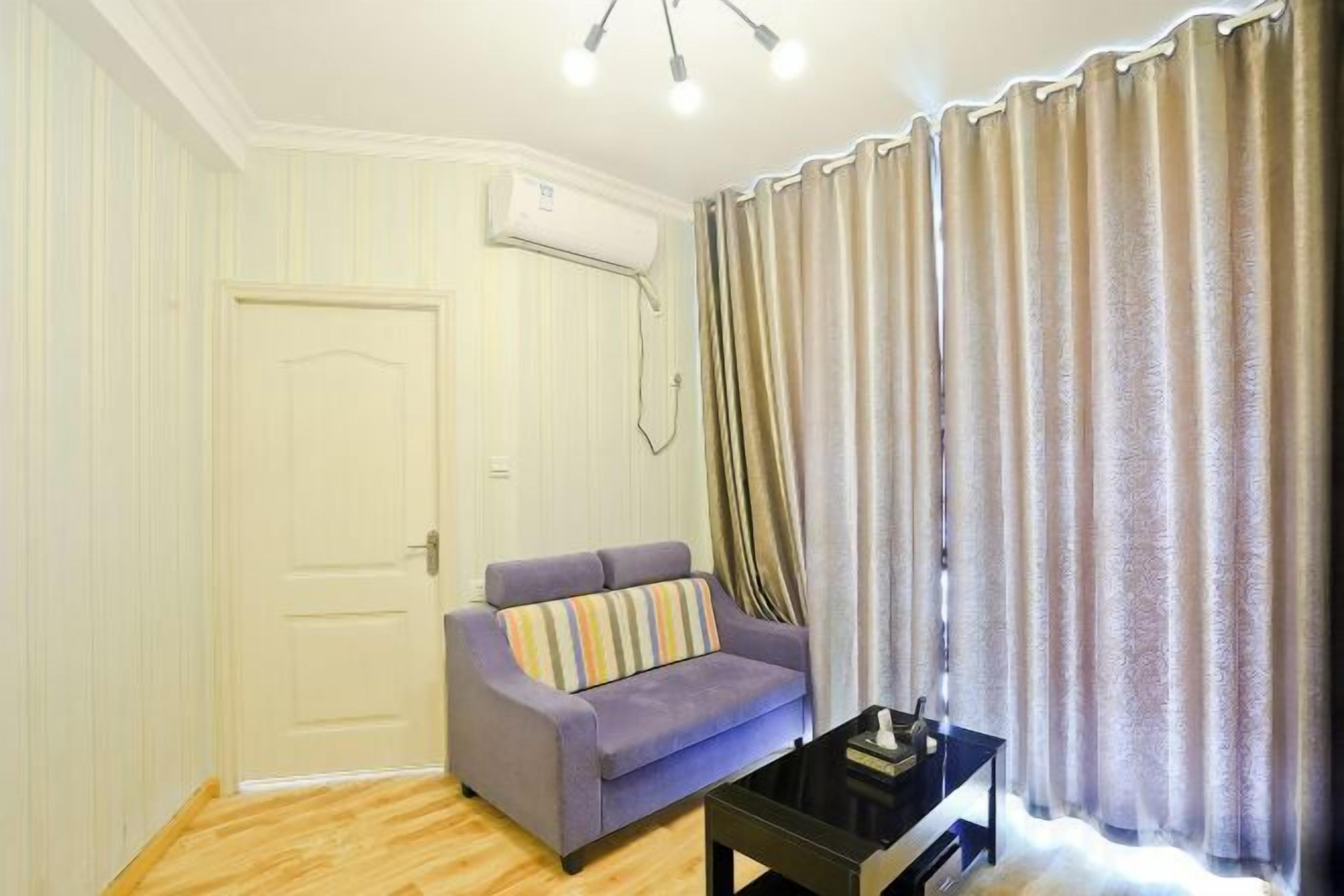 A room with a sofa, a small table, a door, and a curtain.