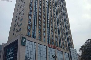 A tall building with a prominent 'V' logo on the facade, multiple windows, and a sign with Chinese characters. - Aishe Apartment (Changsha University of Science and Technology) (Changsha)