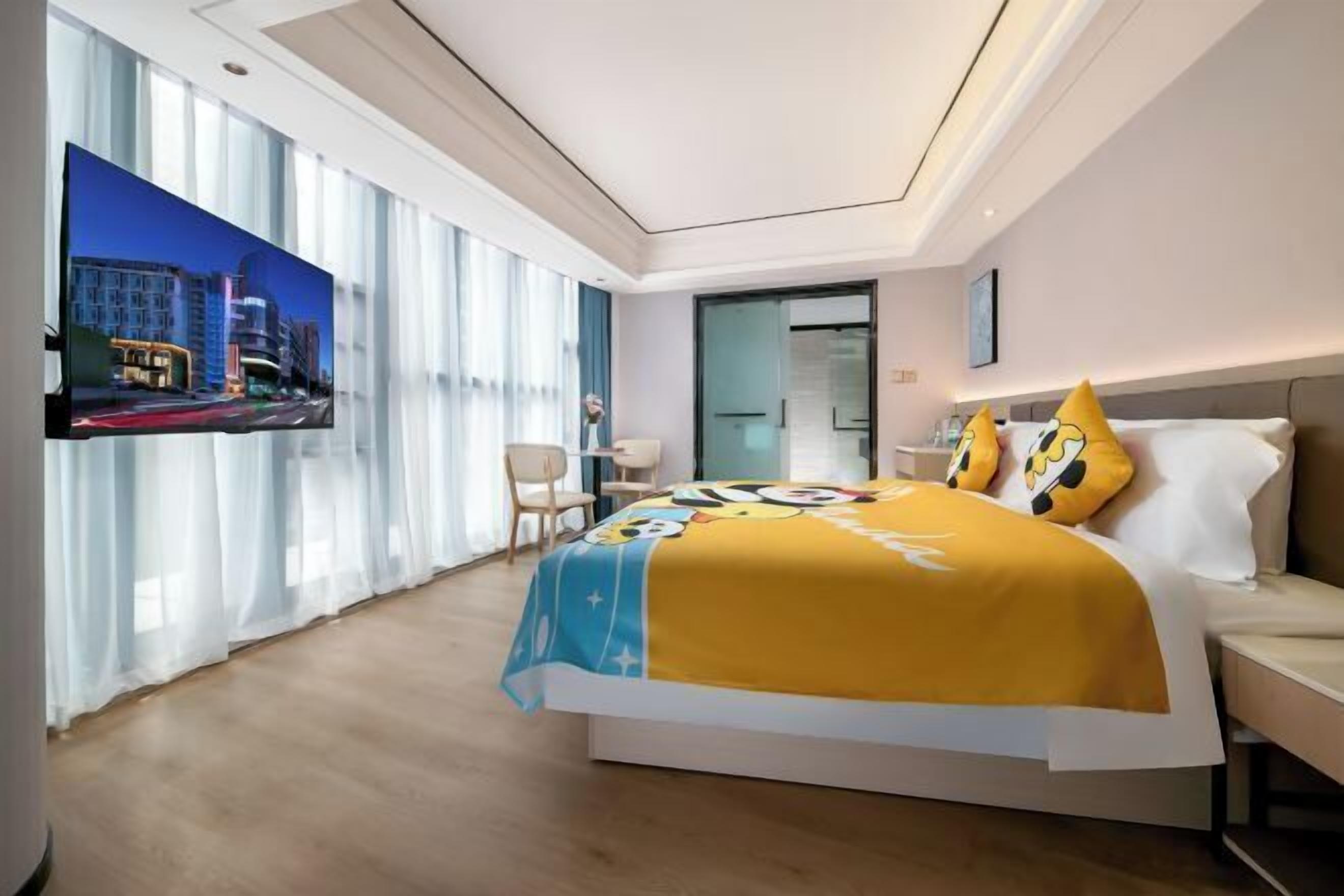 Une chambre d’hôtel moderne dotée d’un grand lit, d’un téléviseur à écran plat et offrant une vue sur la ville.