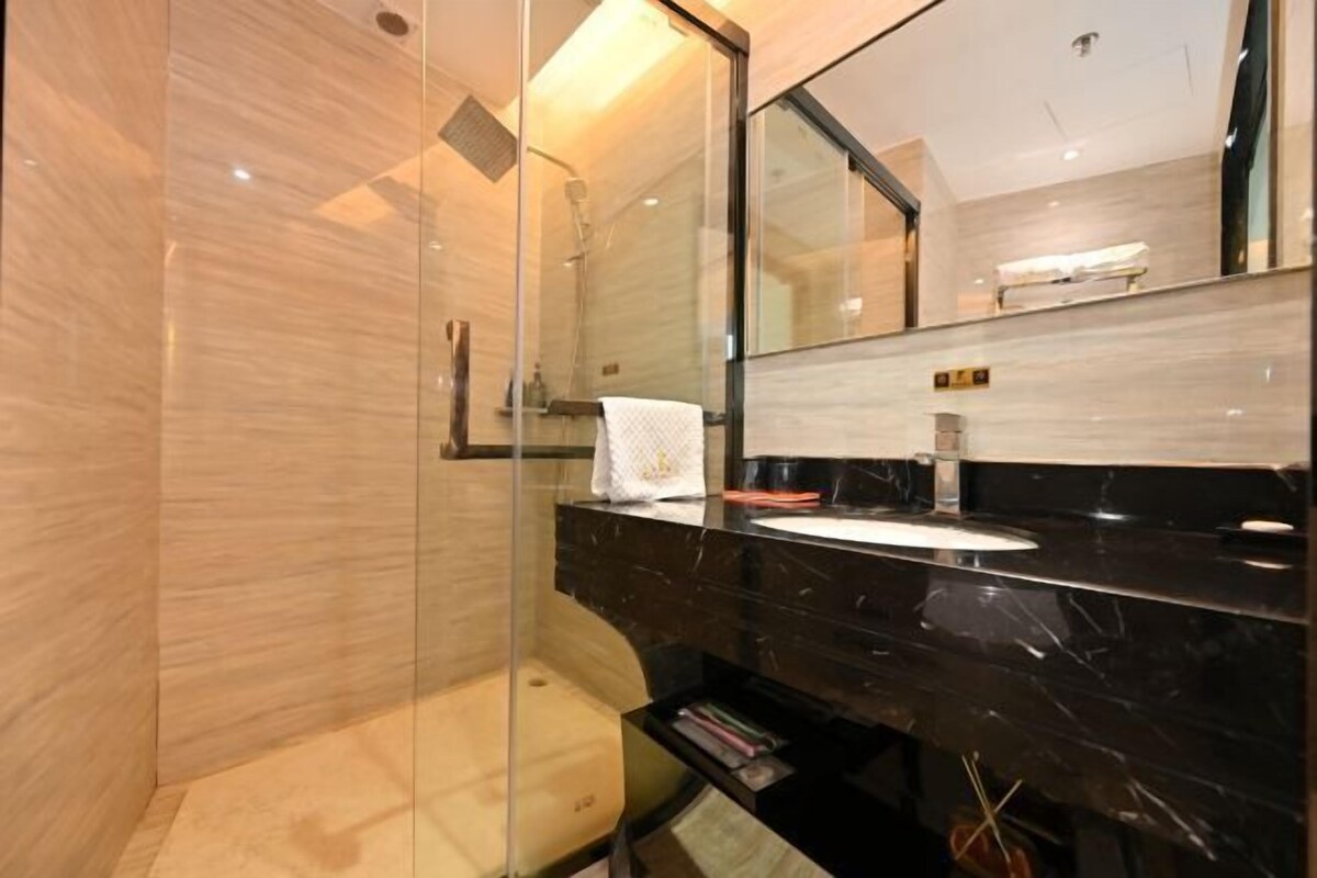 A modern bathroom with a glass shower enclosure, a marble vanity, and a large mirror.