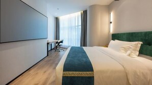 Een moderne hotelkamer met een groot bed, een bureau en een projectiescherm aan de muur.