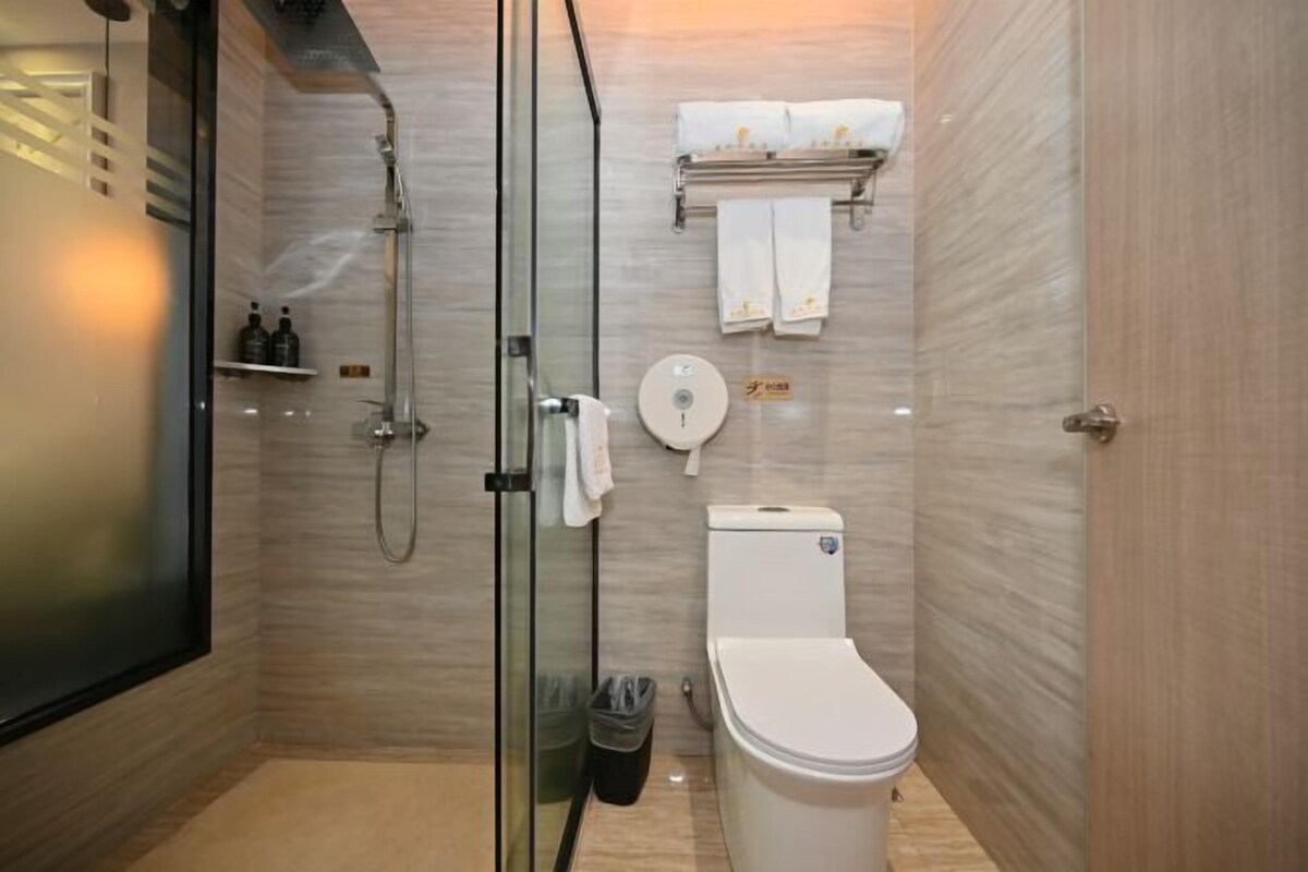 A modern bathroom with a glass-enclosed shower, a toilet, and a towel rack with towels.