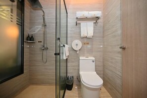 Moderni kylpyhuone, jossa on lasiseinällä varustettu suihku, wc ja pyyhekoukku pyyhkeineen.