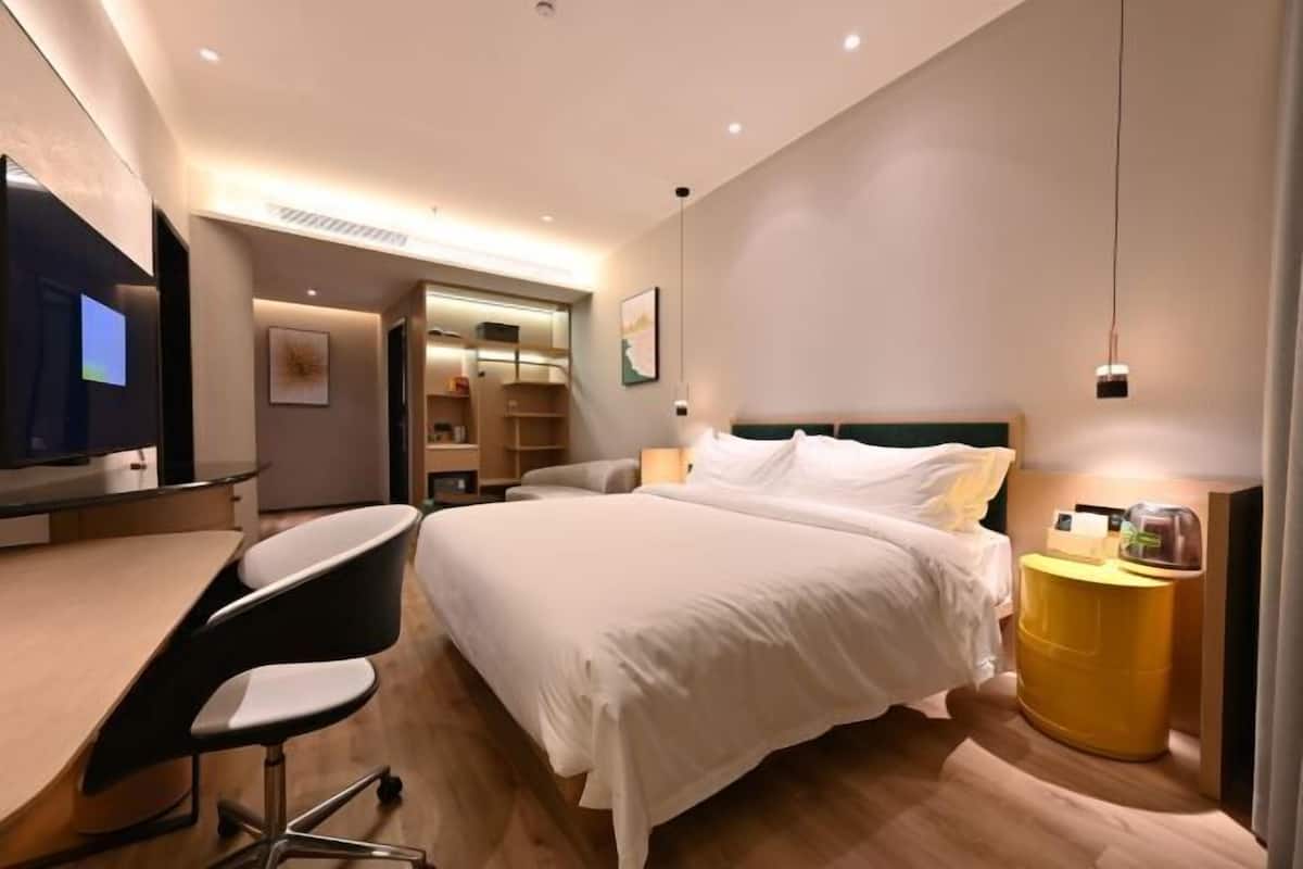 Ein modernes Hotelzimmer mit Bett, Schreibtisch, Stuhl und Fernseher.