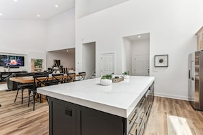 Une cuisine moderne dotée d’un grand îlot central, de planchers en bois et d’un téléviseur à écran plat.