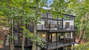 Een chalet met twee verdiepingen en een balkon, omringd door bomen.