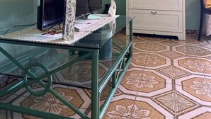 A room with a glass table, a flat-screen TV, a white dresser, a mirror, and a patterned floor. - Garden House B&B - Vesuvius - Cozy accommodation for couples and families (Striano)