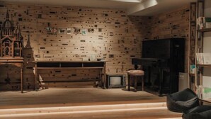 Quarto com parede de madeira, uma pequena mesa, uma televisão e uma estante de livros.