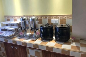 A buffet setup with coffee machines, a water dispenser, and large black containers, likely for beverages. - Shankee Hotel (Yangzhou Jiangdu Longchuan Plaza) (Yangzhou)