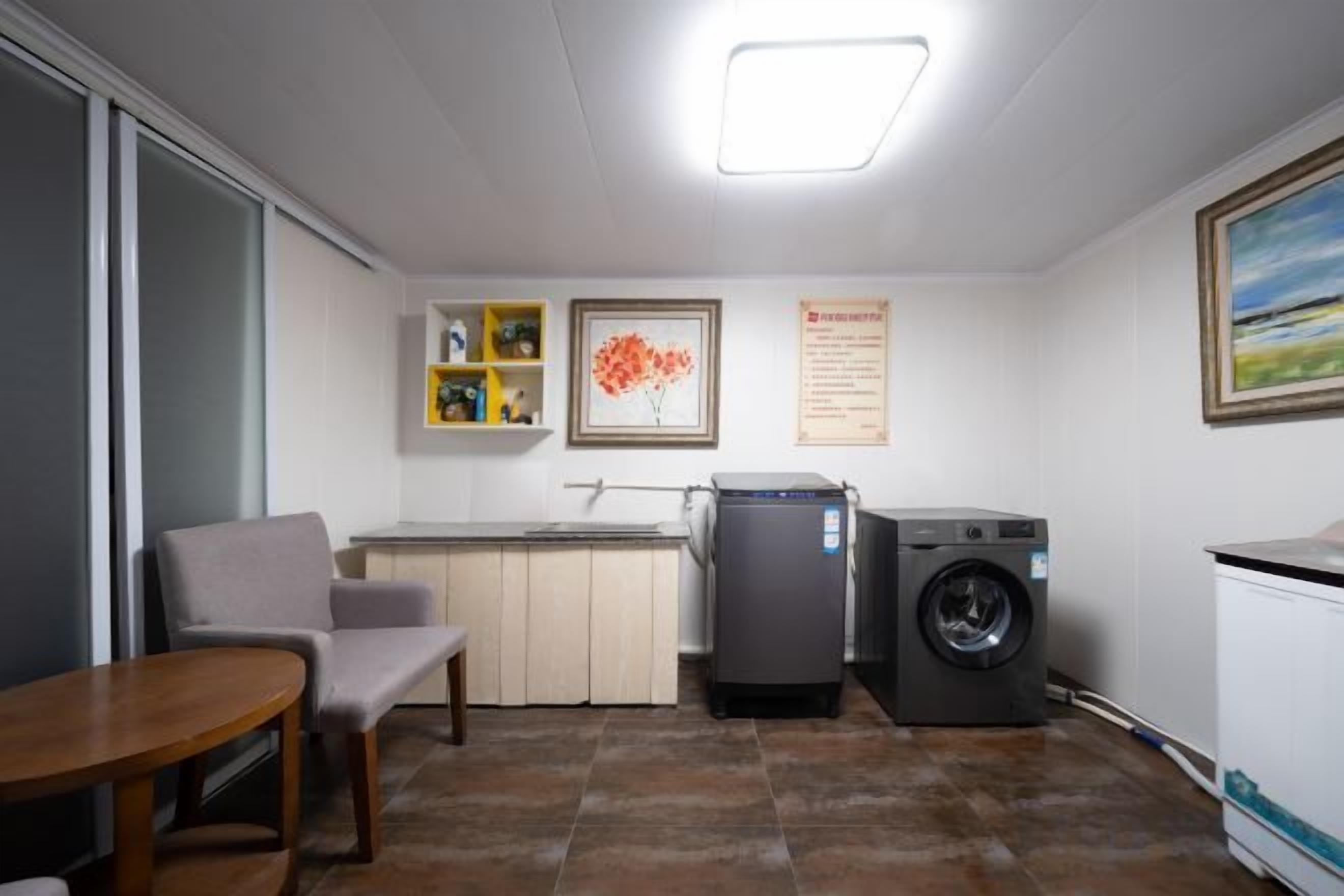 Une cuisine compacte équipée d’un lave-linge, d’une table à manger et d’une chaise.