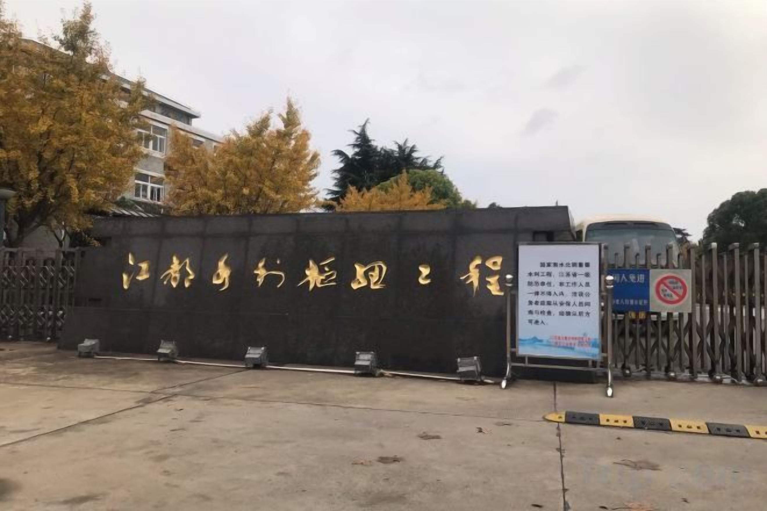 A gated entrance with a signboard, a concrete floor, and a metal fence.