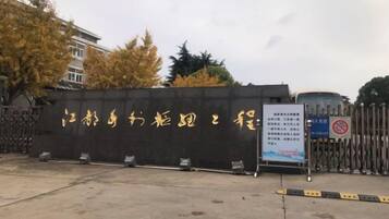 A gated entrance with a signboard, a concrete floor, and a metal fence.