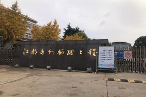 A gated entrance with a signboard, a concrete floor, and a metal fence. - Shankee Hotel (Yangzhou Jiangdu Longchuan Plaza) (Yangzhou)