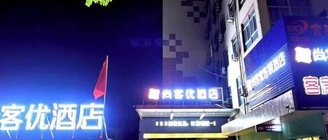 Un hôtel doté d’une enseigne lumineuse, d’un drapeau et d’une façade avec des fenêtres.