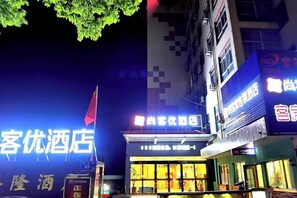 Un hôtel doté d’une enseigne lumineuse, d’un drapeau et d’une façade avec des fenêtres.