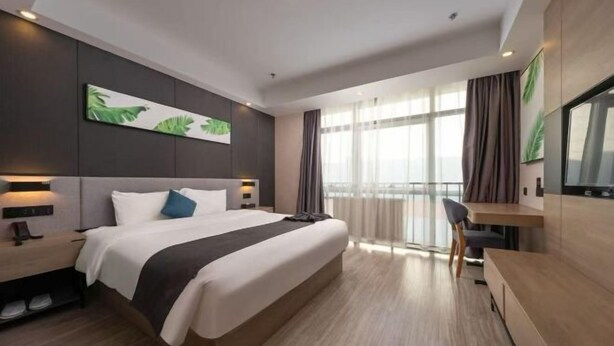 Et moderne hotelværelse med en stor seng, sengeborde, et skrivebord og udsigt til det fri.