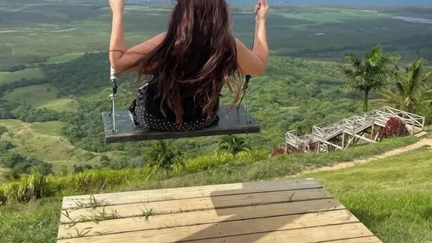 A person on a swing overlooking a lush landscape with a wooden platform in the foreground. - Sol Caribe apartahotel Punta Cana  (Punta Cana)