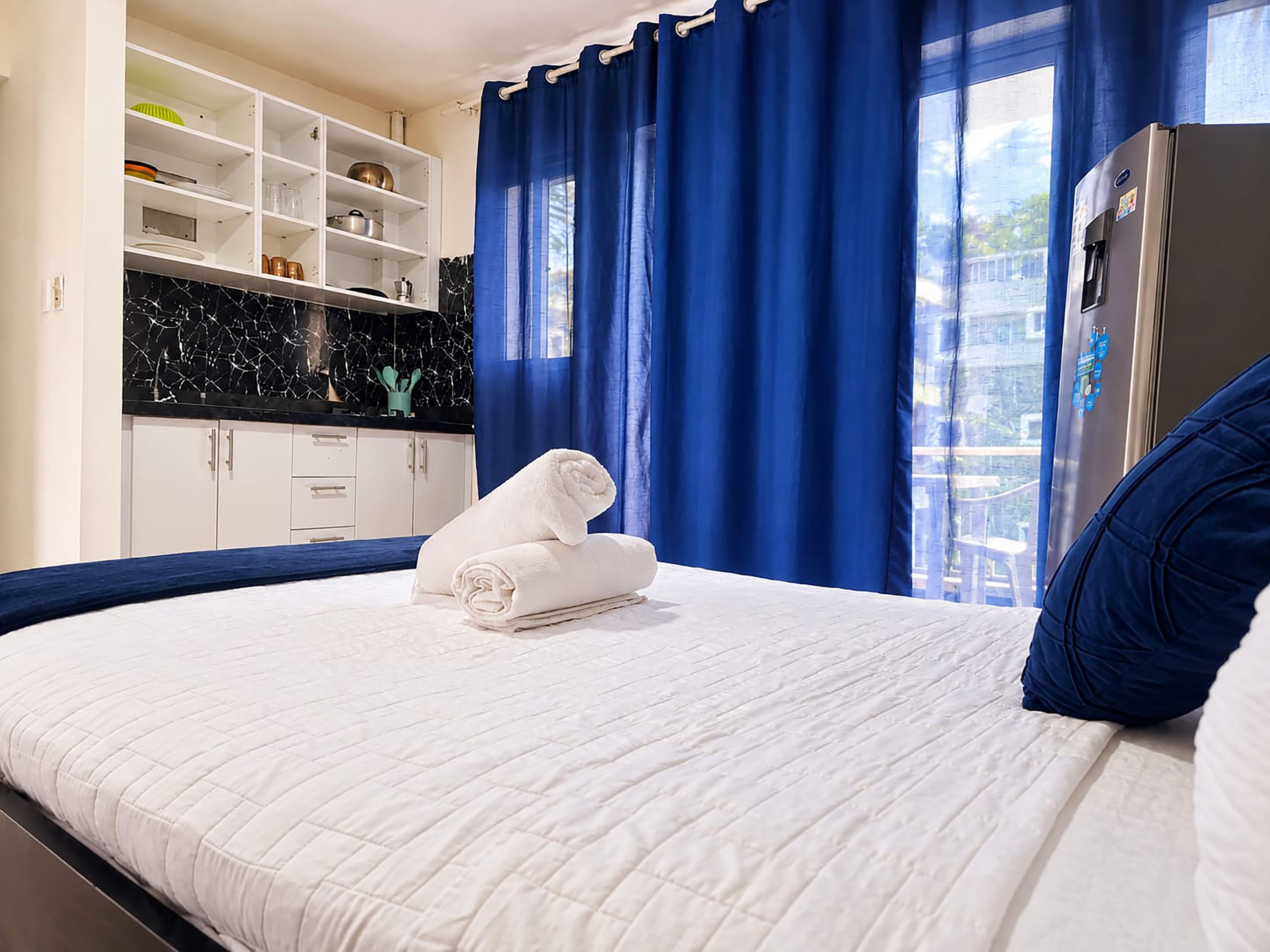 Ein Hotelzimmer mit einem Bett, einem Kleiderschrank, einer Küchenzeile und einem Kühlschrank.