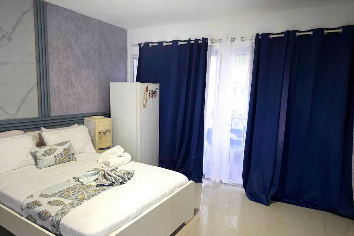 Een hotelkamer met een bed, een kledingkast, een klein tafeltje en een raam met gordijnen.