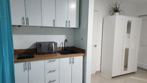A kitchen with white cabinets, a microwave, and a sink. - Sol Caribe apartahotel Punta Cana  (Punta Cana)