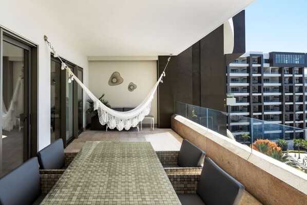 Un balcón con hamaca, zona de estar y vista panorámica de la ciudad.