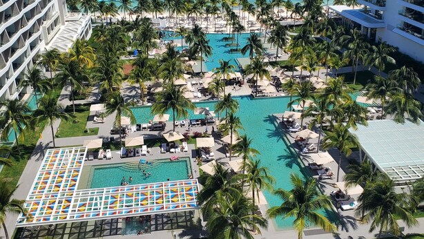 Un resort con diverse piscine, palme e vista sull'oceano.