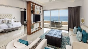 Una camera d'albergo moderna con un balcone, un letto, una televisione e una zona relax vista mare.