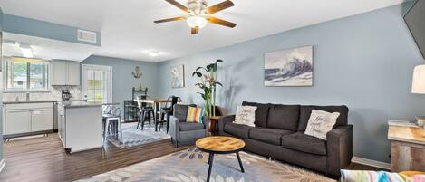 A modern living room with a sofa, coffee table, and a dining area with chairs.