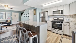 A modern kitchen with a central island, stainless steel appliances, and a herringbone-patterned backsplash.